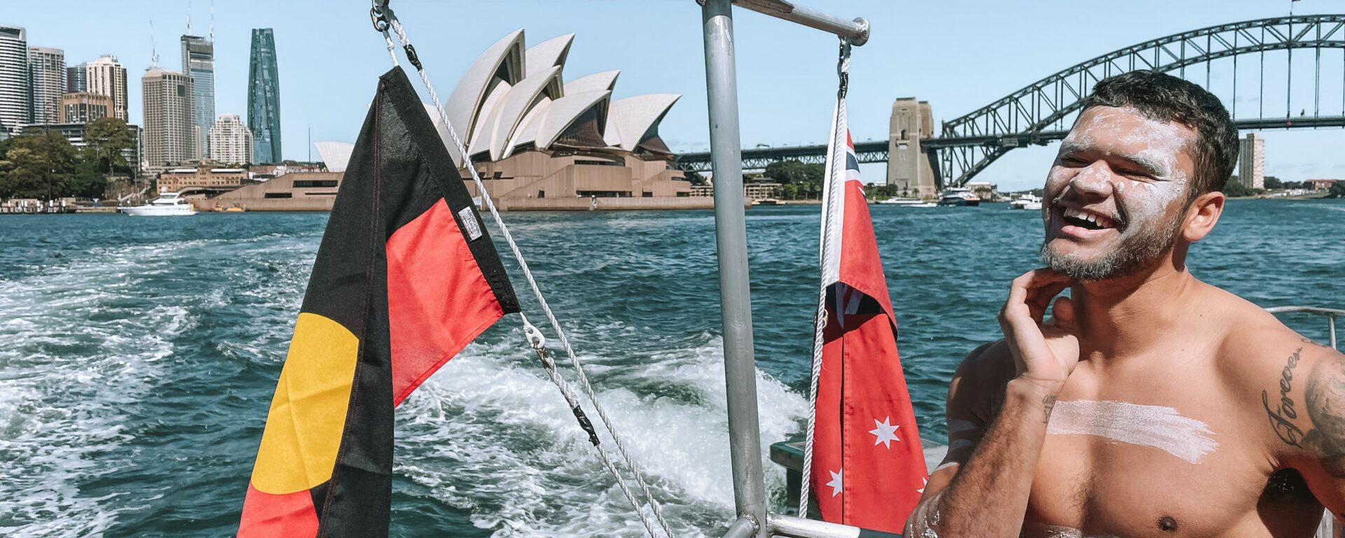 Man standing next to an aboriginal flag on a Sidney Ferry