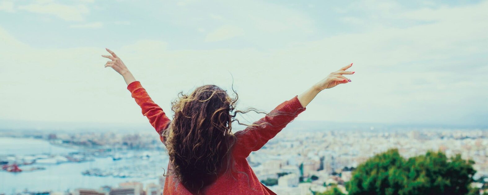 Femme de dos avec une veste rouge regardant au loin