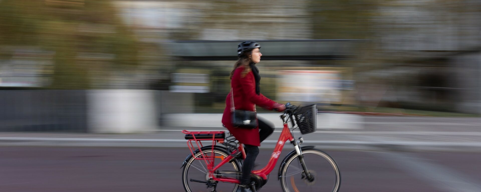 Jeune femme avec un manteau rouge sur un vélo rouge