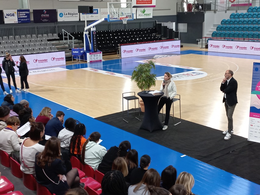 Terrain de basket - Femme au micro assistance sur les gradins- Bannières Transdev autour du terrain