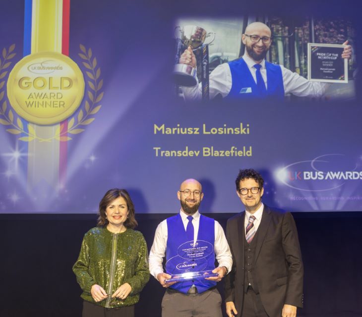 Mariusz Losinski on stage at the UK Bus Awards with his Gold trophy, BBC News host Jane Hill and Robert Jack, editor of road and rail industry journal Passenger Transport